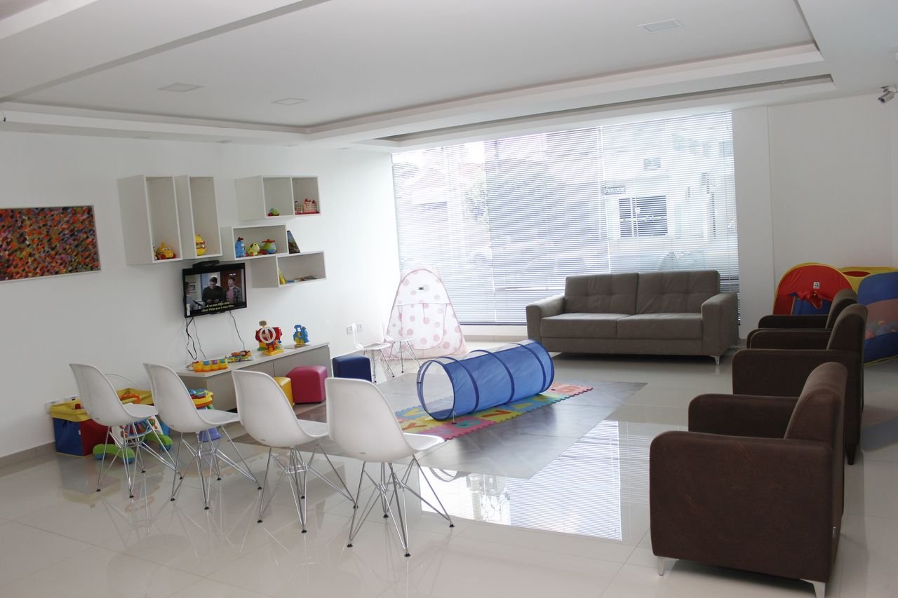 Área infantil com brinquedos e assentos para acompanhantes